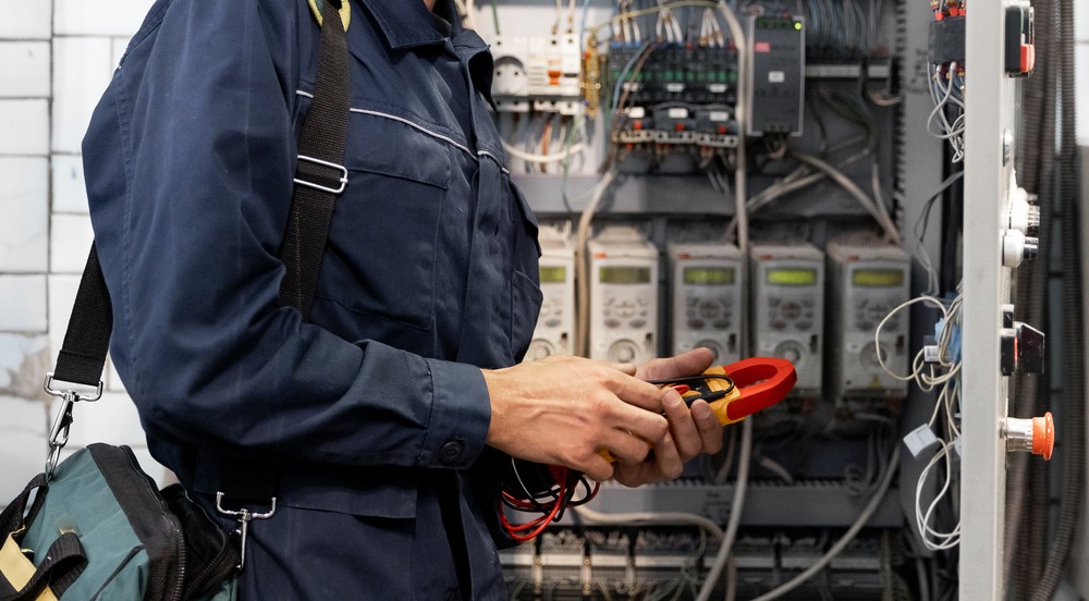 Commercial electrician in Brisbane working on an electrical panel with a multimeter
