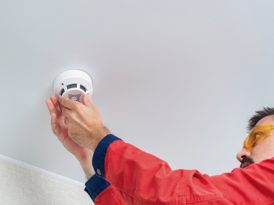 Technician performing smoke alarm installation Brisbane