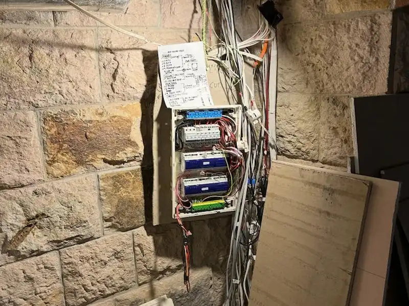 Old sub-board with messy wiring on a brick wall before rewiring by SEQ Sparky in Brisbane
