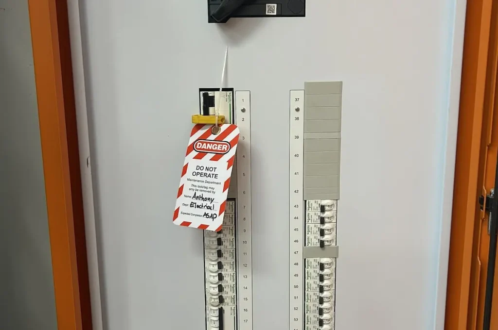 Brisbane electrical lockout tagout procedure showing yellow safety tags applied to switchboard main switch isolating circuits before energising during SEQ Sparky compliance work