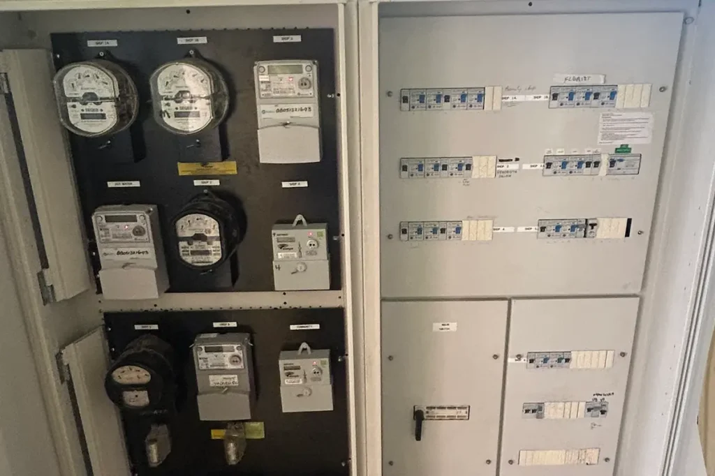 Modern multi-meter RCBO switchboard in Brisbane home with old analogue meters retained on left and fresh RCBO protection section on right after SEQ Sparky staged upgrade